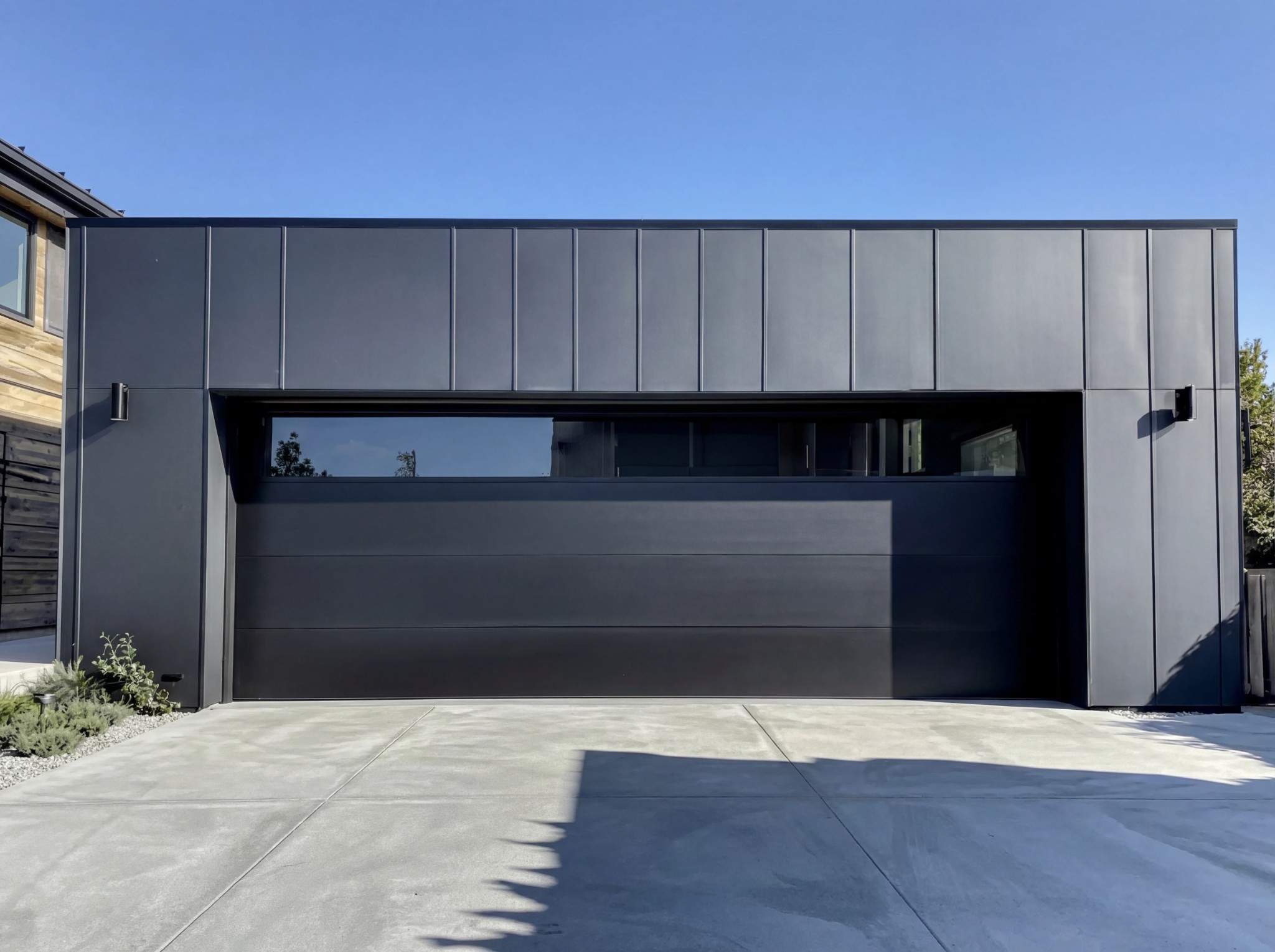 Nowoczesna ciemna elewacja budynku modułowego z garażem